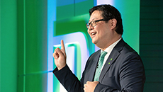 TD CFO Xihao Hu wears a green tie while talking at a conference.