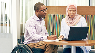A TD employee that uses a wheelchair collaborates with a colleague that wears a hijab.