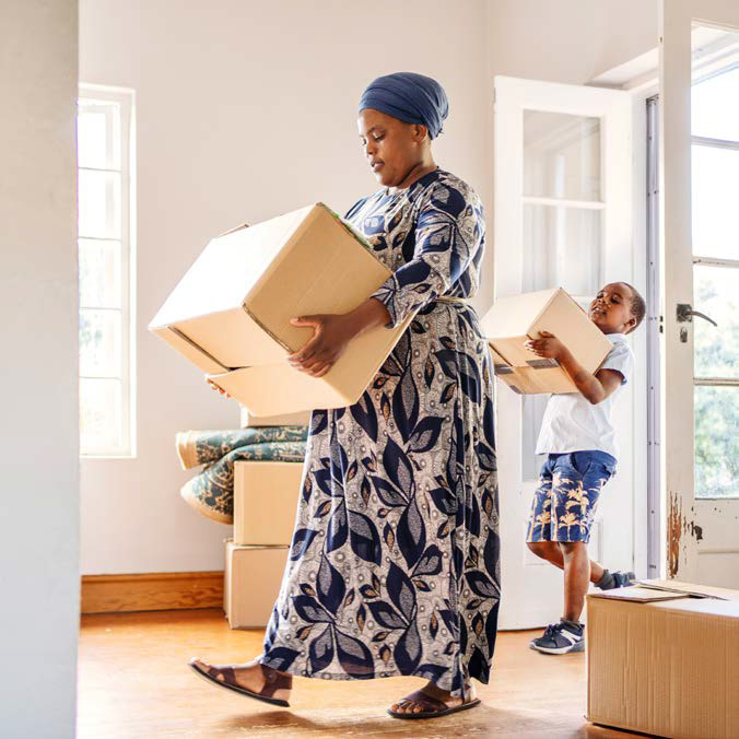 Mother and son carrying boxes into new home